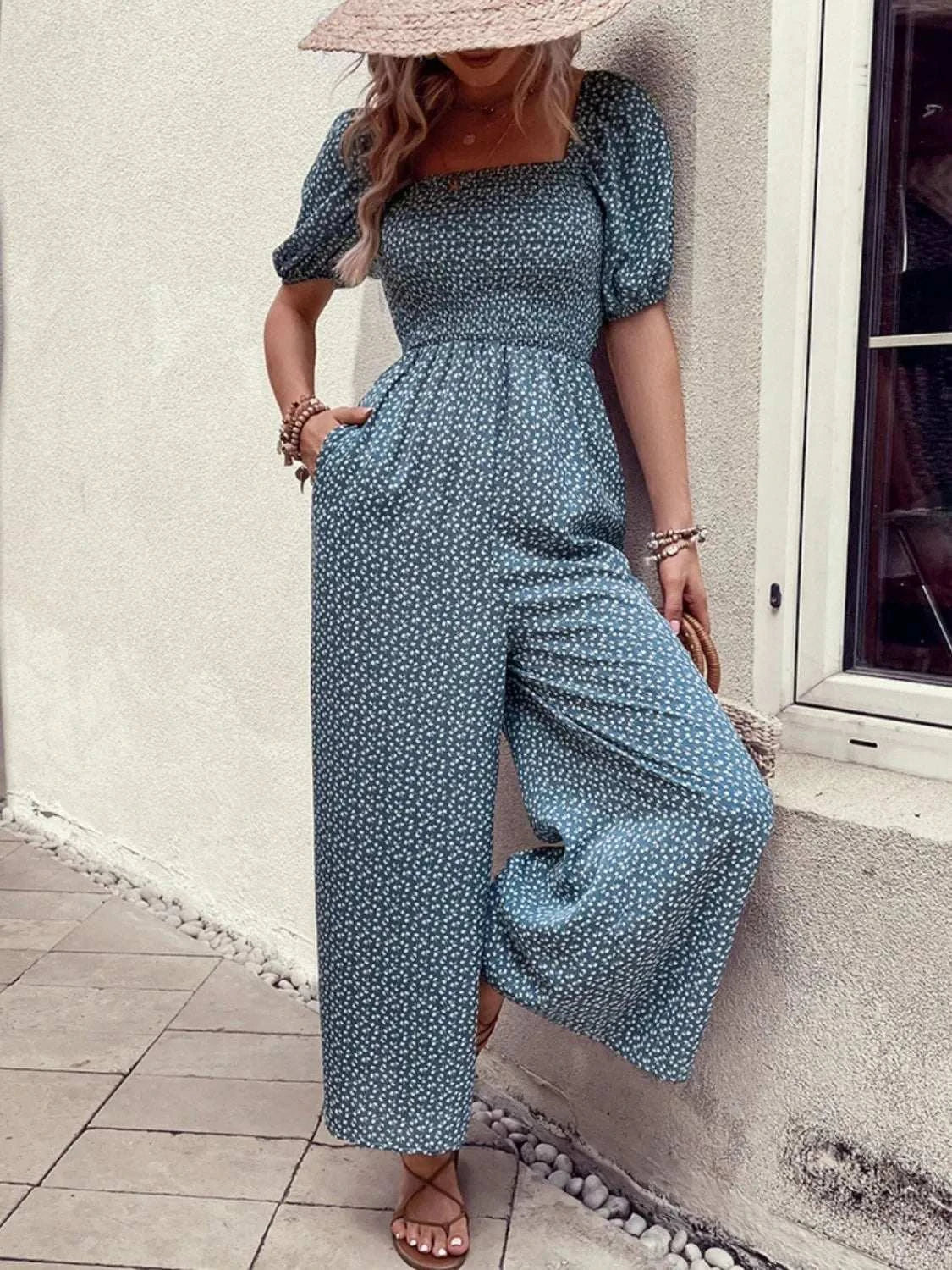 Woman wearing a printed square neck puff sleeve jumpsuit with smocked waist and pockets
