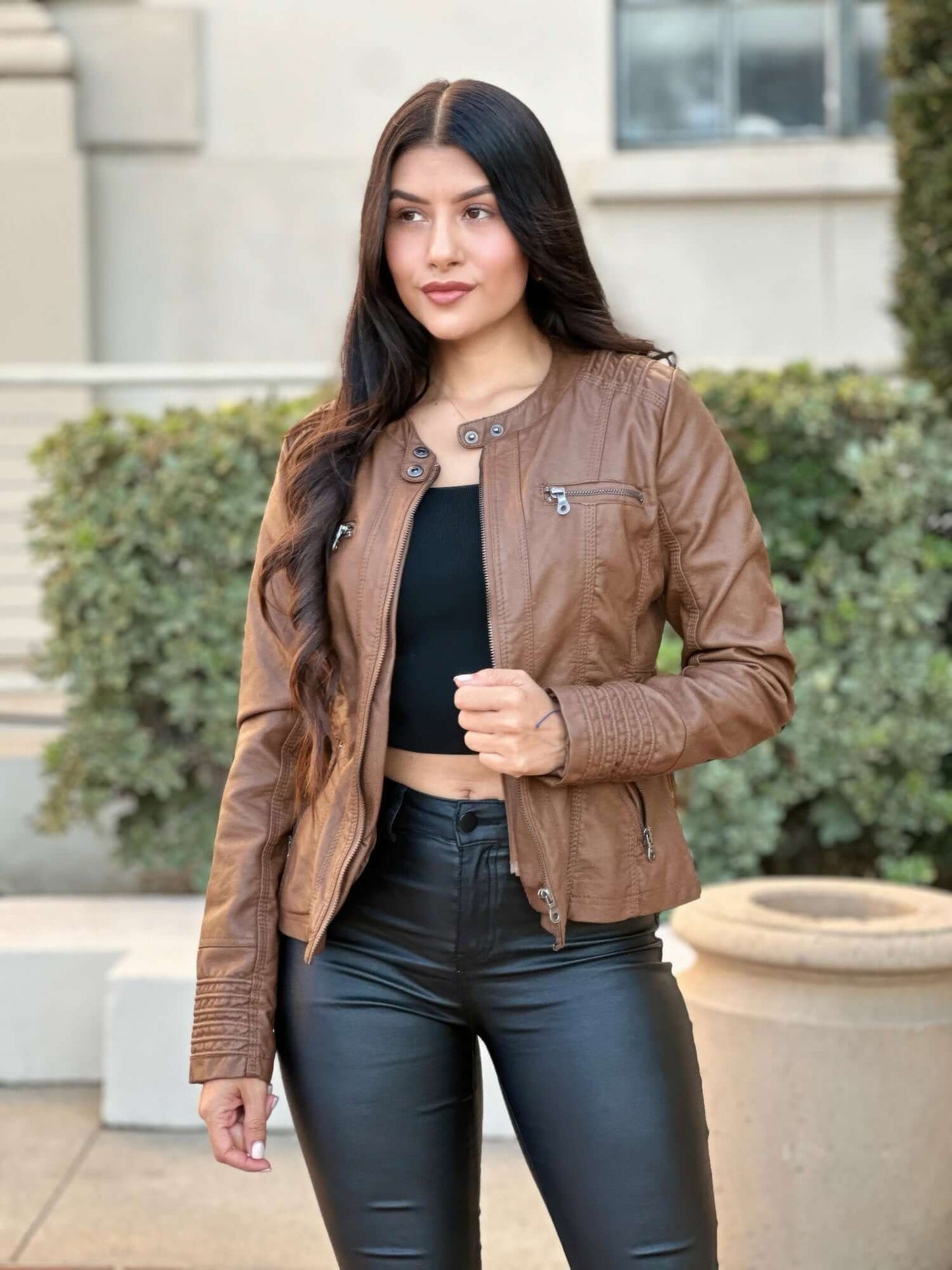 Woman wearing a hooded faux leather jacket with zipper closure and stylish casual look